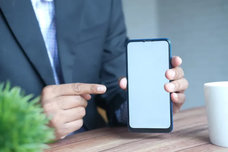 Homme en costume montrant un écran de smartphone